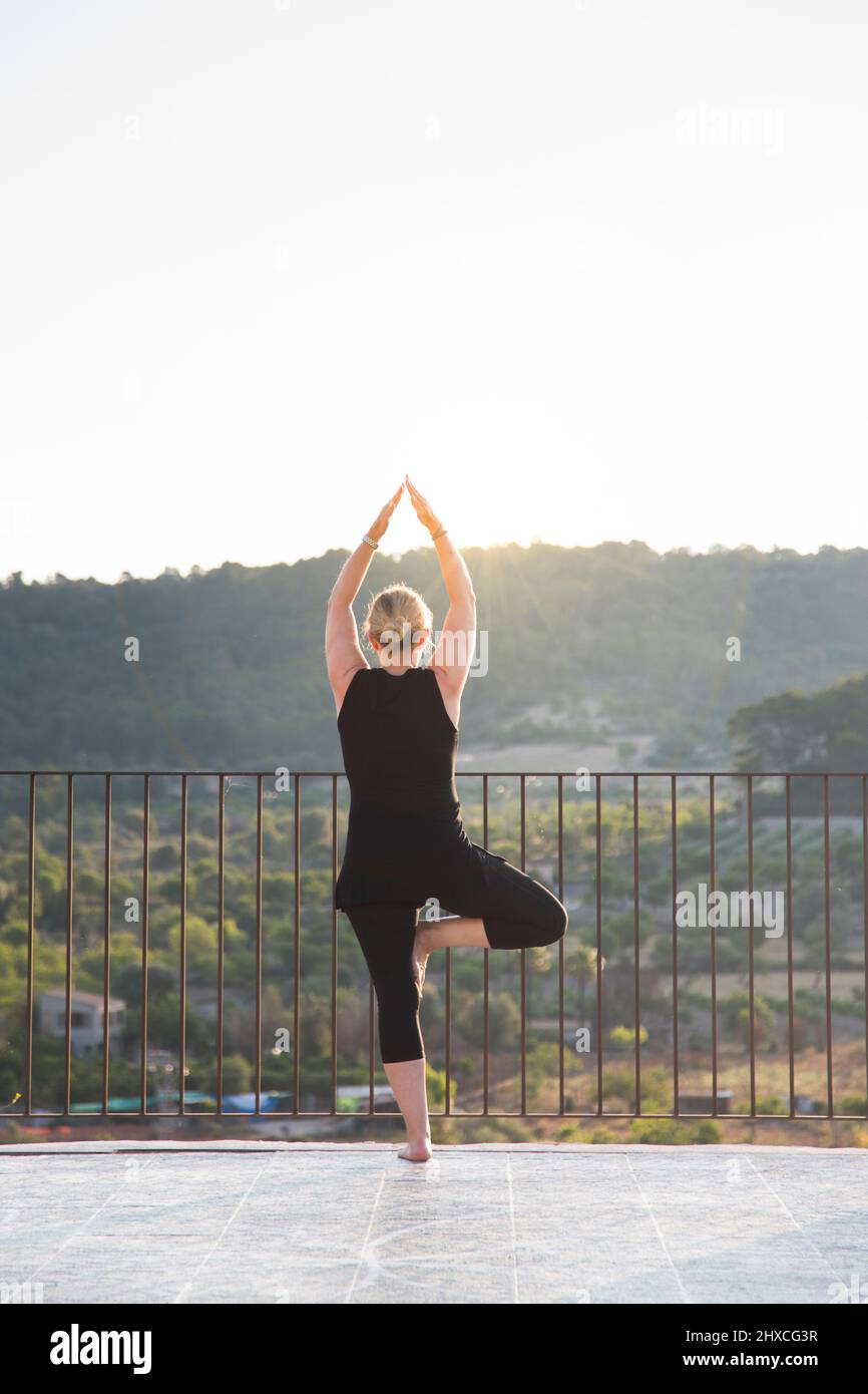 Woman practicing yoga outdoors with view of valley Stock Photo