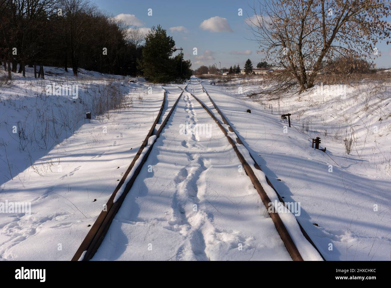 Old unused railway tracks in winter, snowy landscape, traces of people in the snow Stock Photo