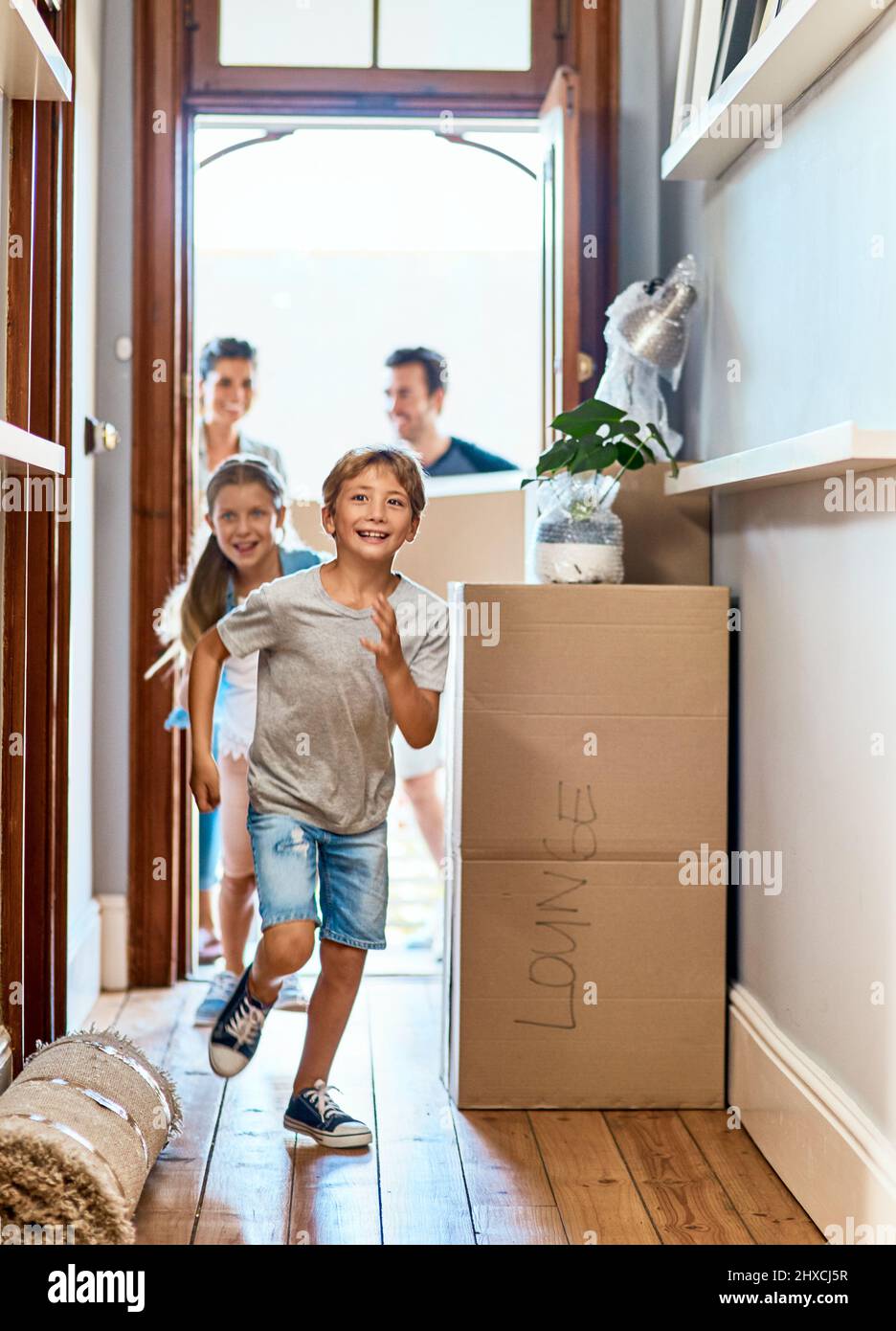 Off to go pick their rooms. Shot of a cheerful young boy and girl running in a hallway in their new home while having fun inside during the day. Stock Photo