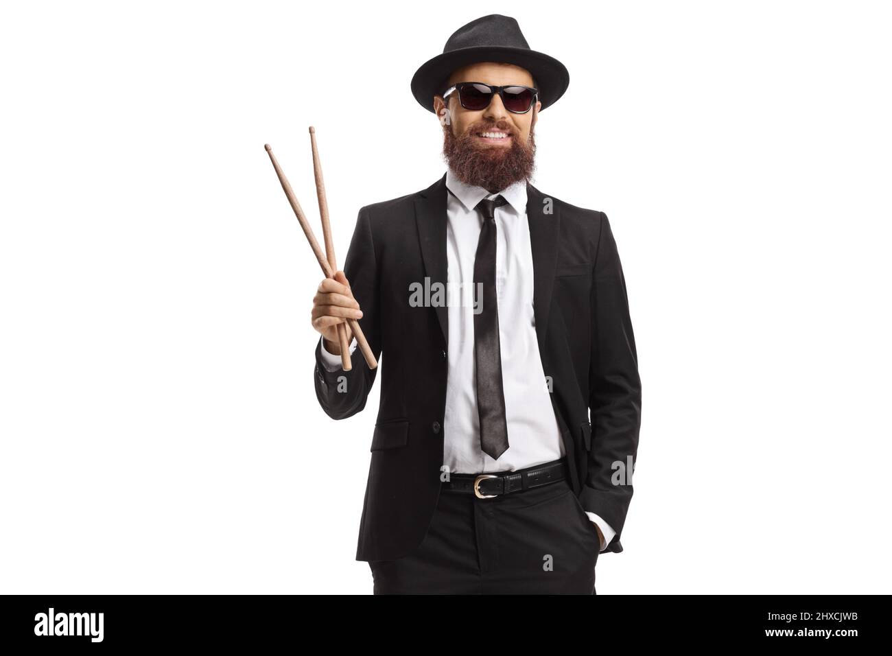 Man in a black suit holding a pair of drumsticks isolated on white background Stock Photo