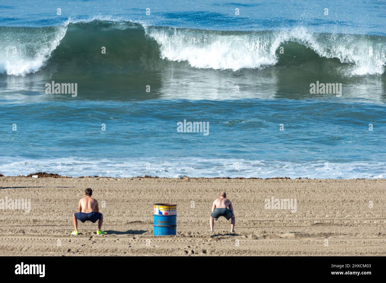 2 athletes doing gymnastics in front of big waves, Santa Monica, California, Stock Photo