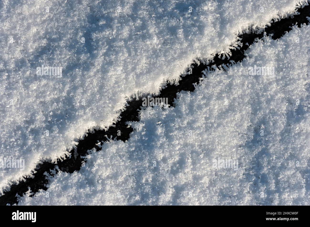 Snow with ice crevice on lake in sunlight, Halland, Sweden Stock Photo