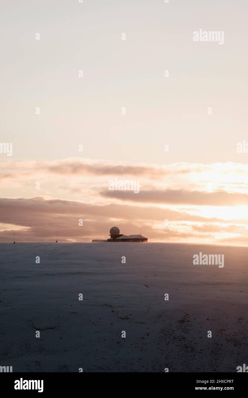 radio antenna station / observatory on snow covered hill during sunset in Norway at Nordkap Stock Photo