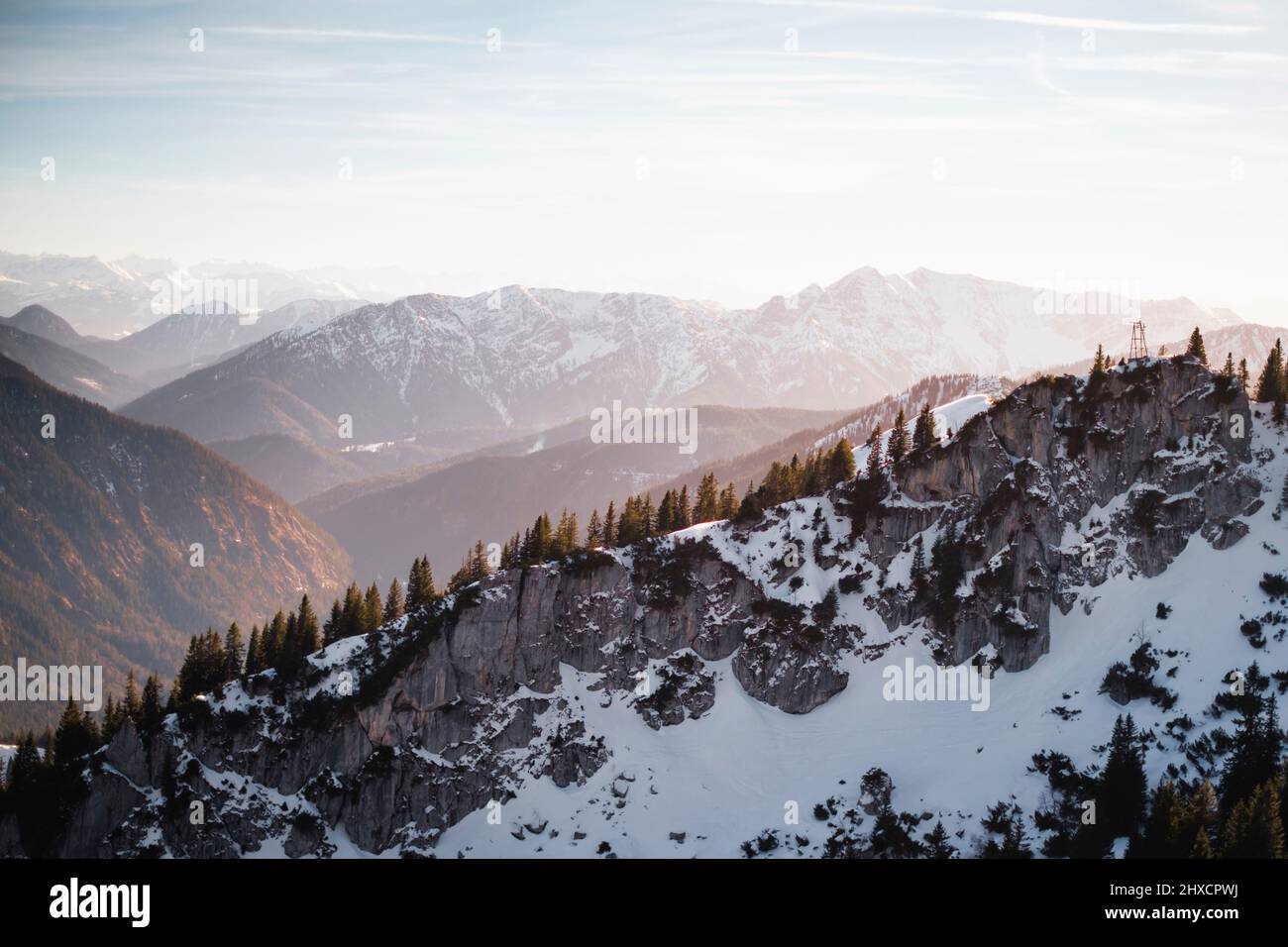 Landscape image with layers of partly snow covered mountains during sunset Stock Photo
