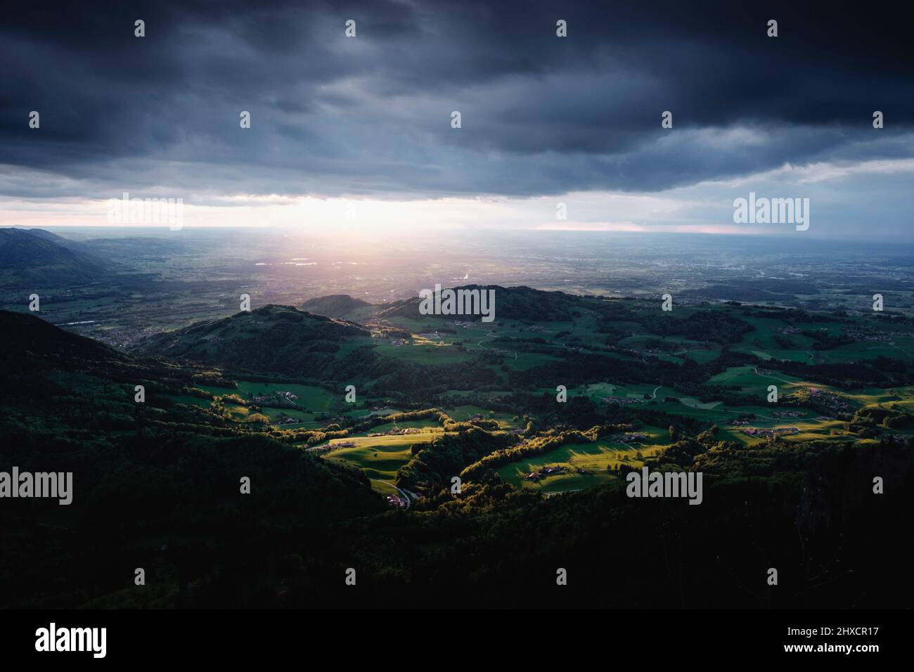 Landscape image of green valley hit by sunlight under rainy clouds at sunset Stock Photo