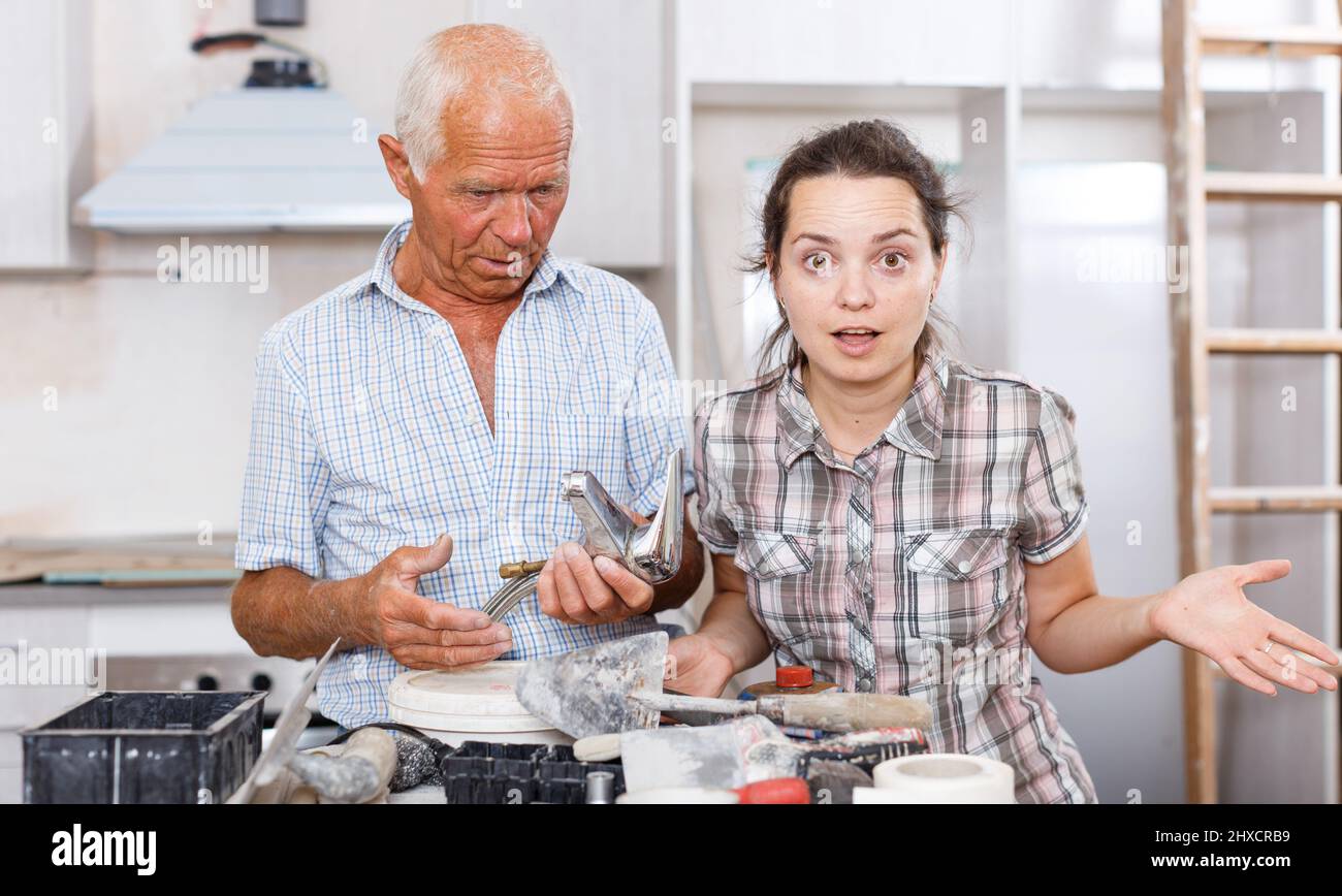Woman and elderly father discussing installing faucet Stock Photo