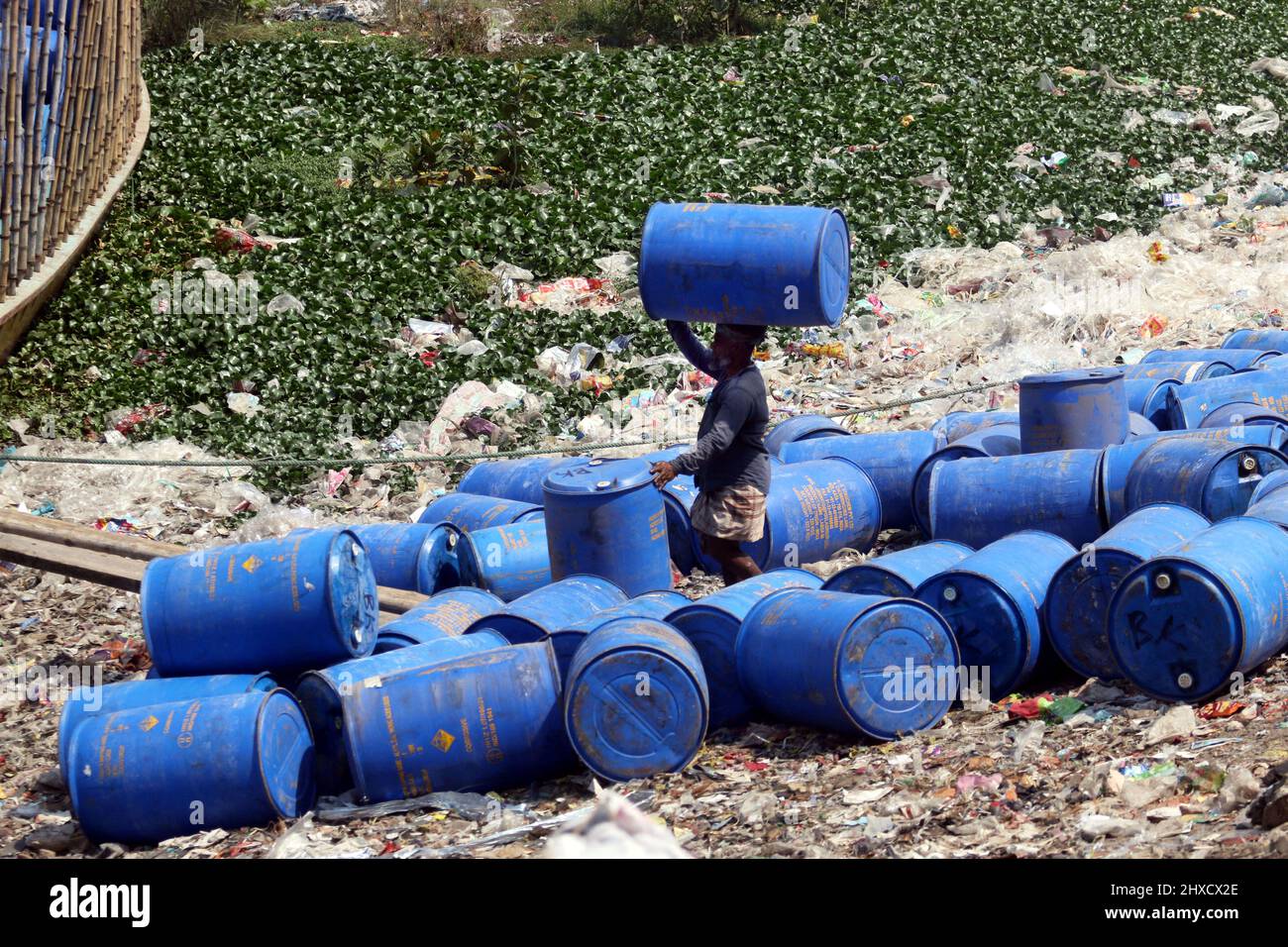 Workers take used drums for recycling at a warehouse in Dhaka