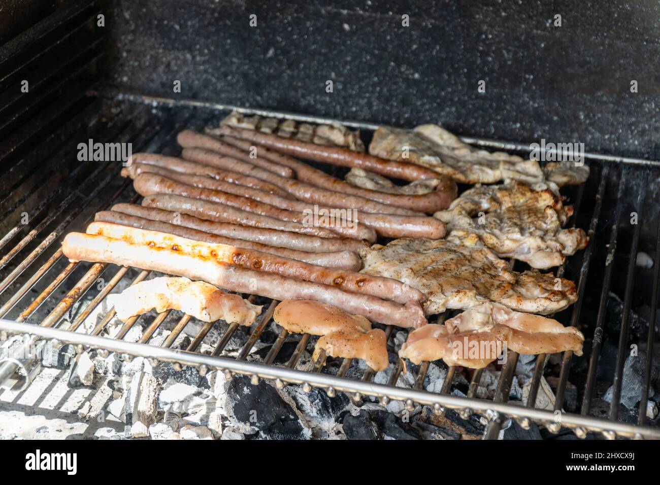 Variety of meats being grilled on a charcoal barbecue Stock Photo - Alamy