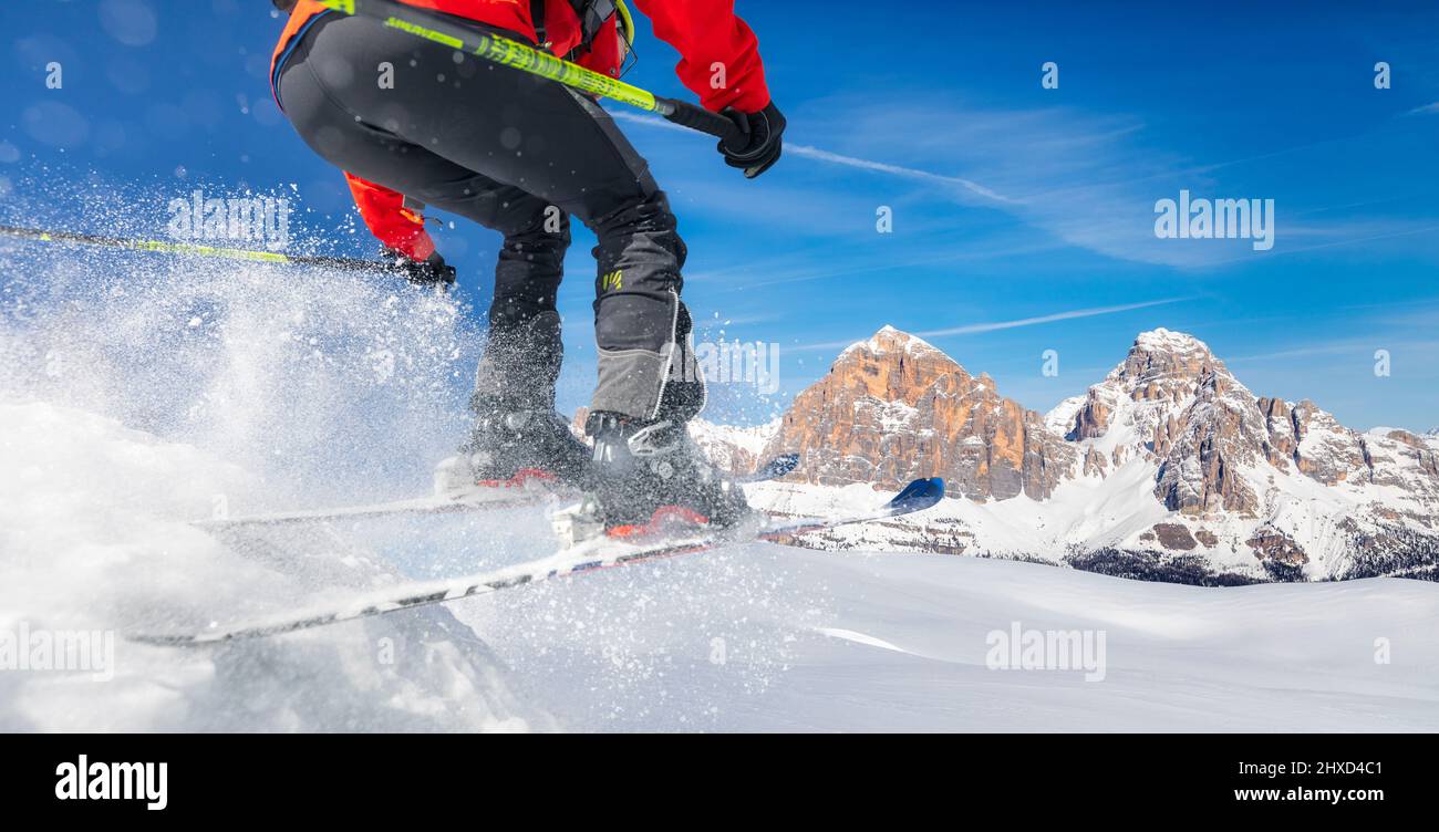 Europe, Italy, Veneto, Belluno province, skitourer while performing a jump on fresh snow, on the background the Tofane, Dolomites Stock Photo