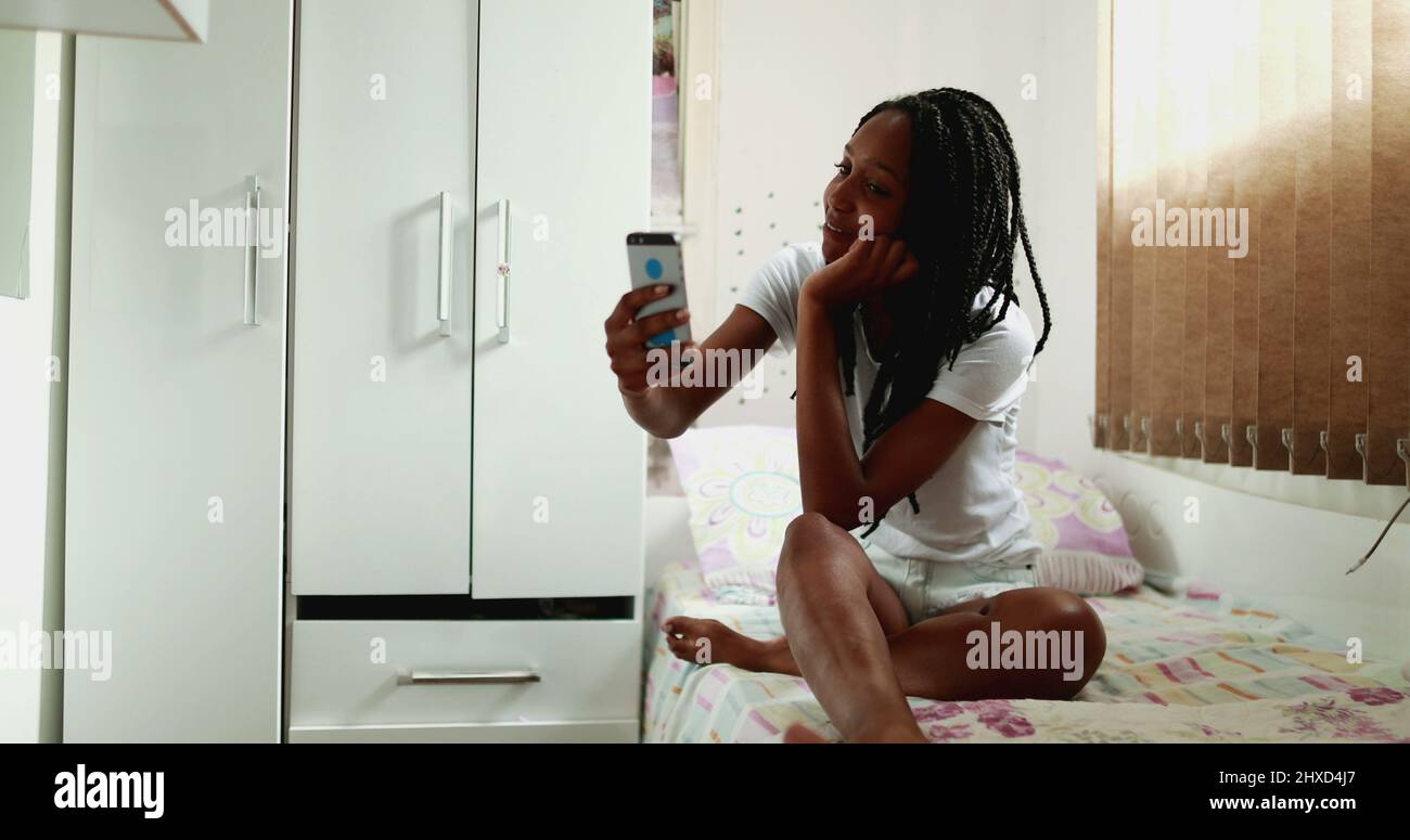 Happy candid teen girl speaking on phone with video communication Stock