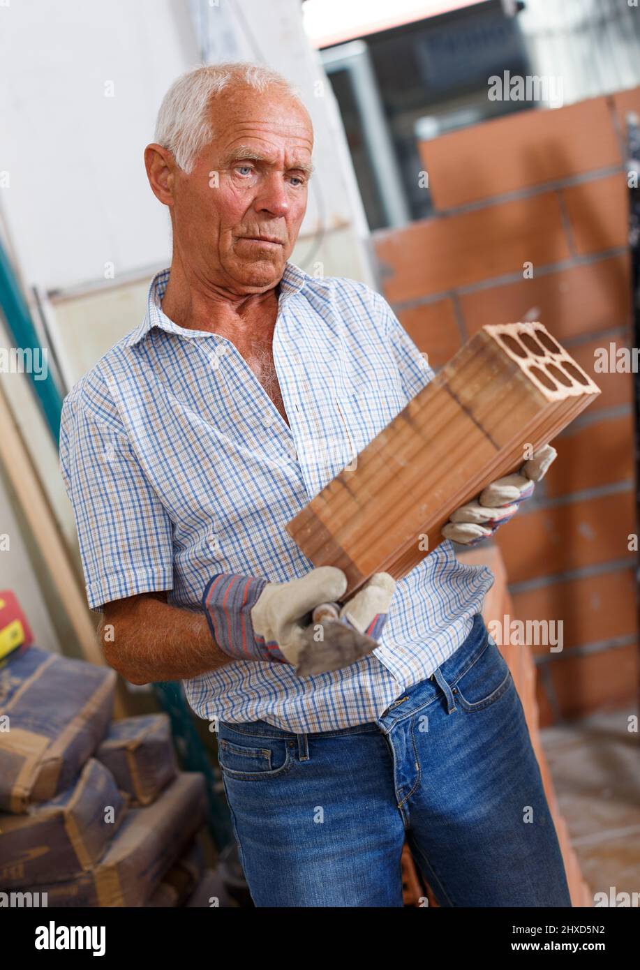 Man inspecting brick for installing wall Stock Photo