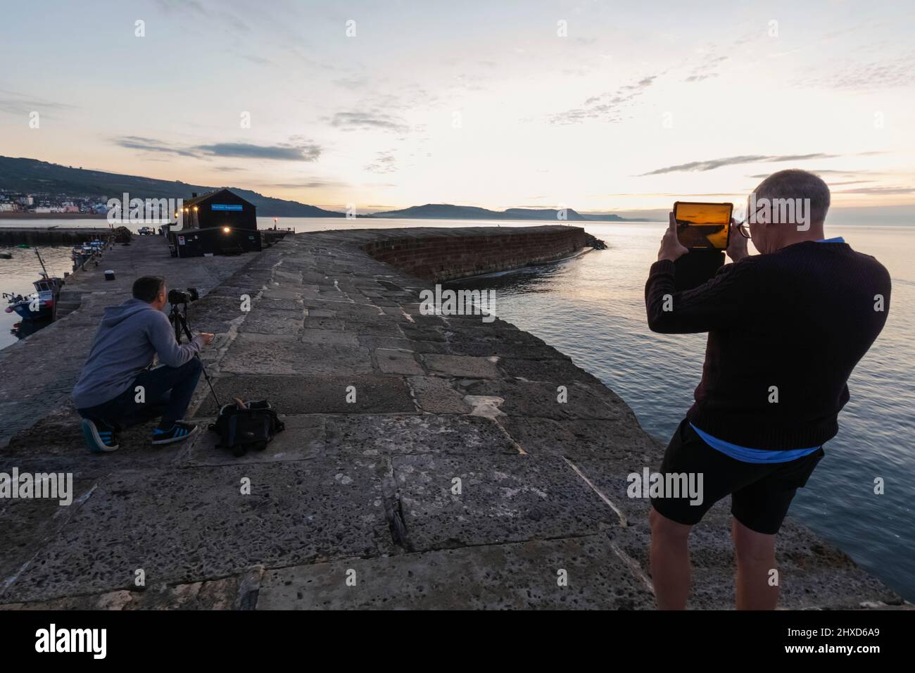 England, Dorset, Lyme Regis, Photographers Taking Pictures on The Cobb at Dawn Stock Photo