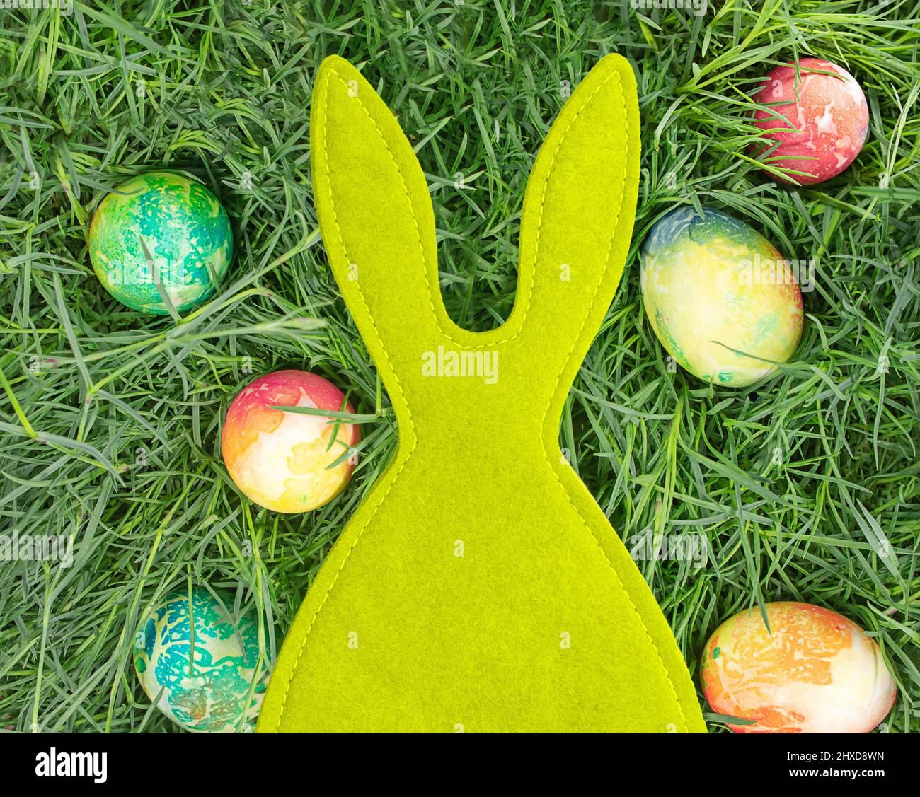 Green felt rabbit with colored eggs. Easter. Copy space Stock Photo