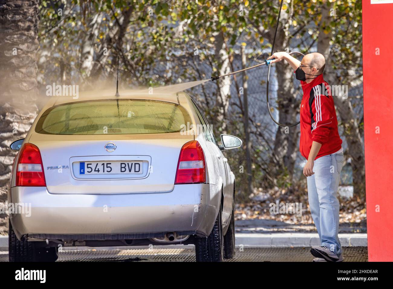 Huelva, Spain - March 9, 2022: An unidentified man is cleaning his car using a high pressure water at service station Stock Photo