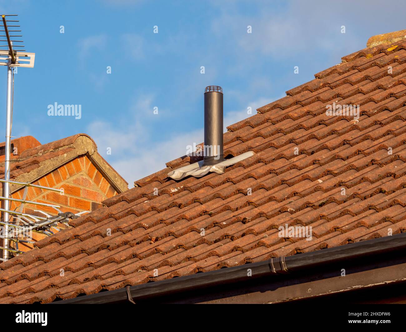 Typical domestic tiled house roof with Vent pipe protruding through tiles. Stock Photo
