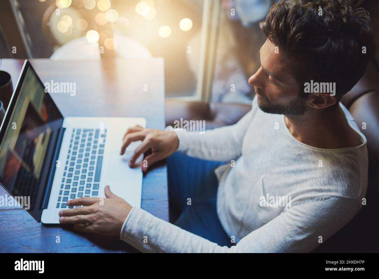 His blog is coming along nicely. Cropped shot of a young man using his laptop in a coffee shop. Stock Photo