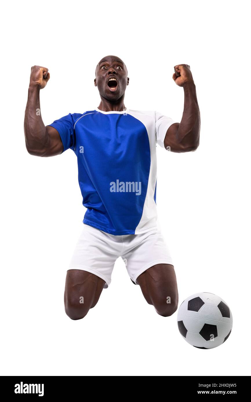 Excited male african american soccer player kneeling while celebrating goal over white background Stock Photo