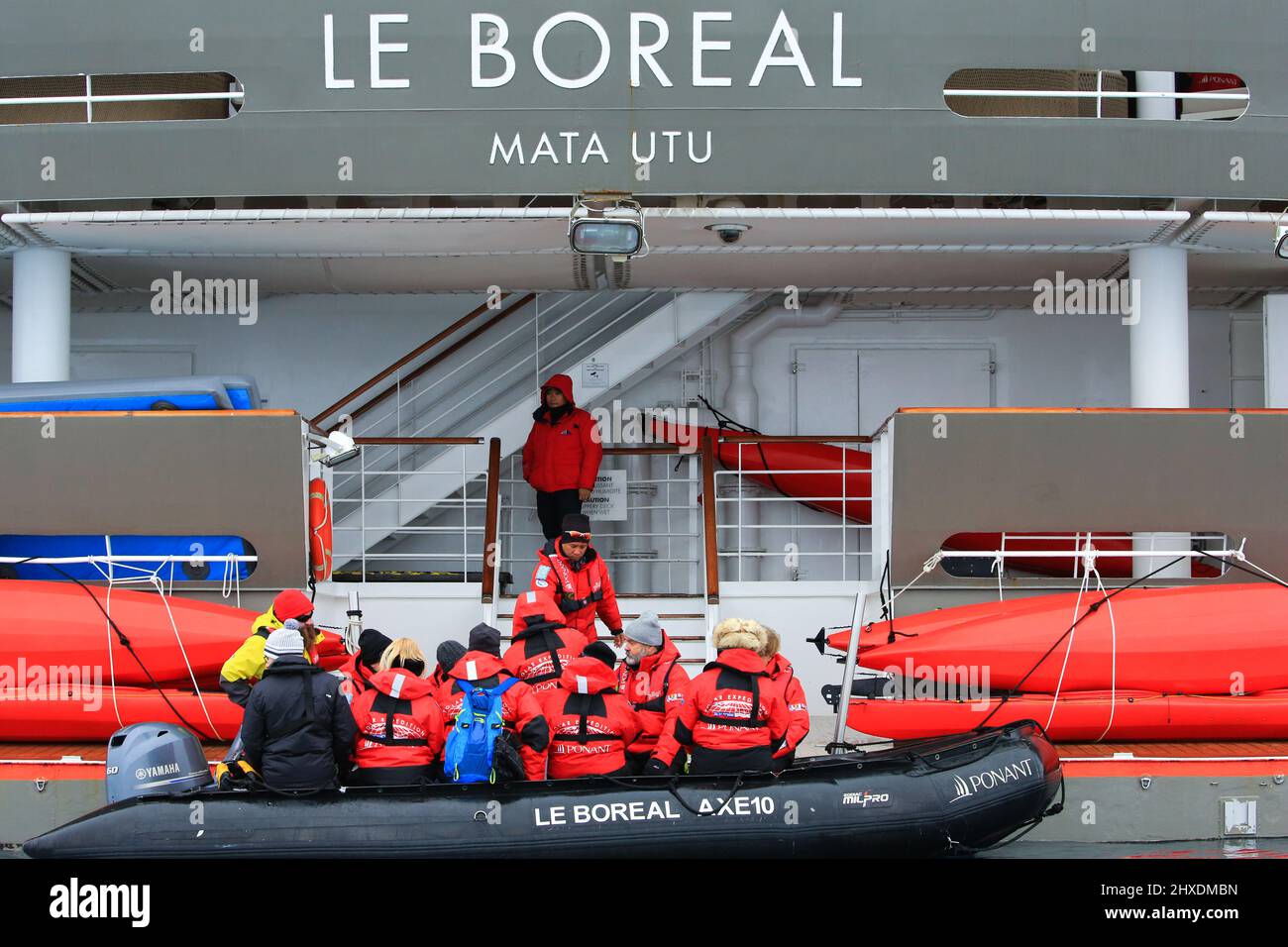 Passengers from the Ponant cruise ship Le Boreal are returning to the ship after visiting the Gentoo penguin colony on Cuverville Island, Antarctica. Stock Photo