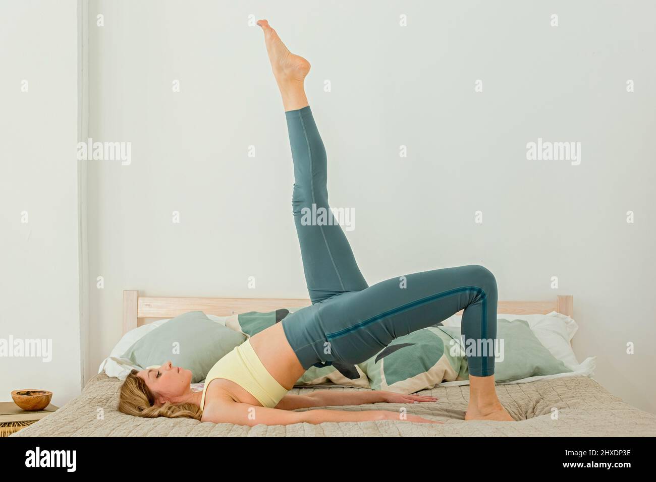 Slender woman in green leggings, performs a yoga exercise, lying on her