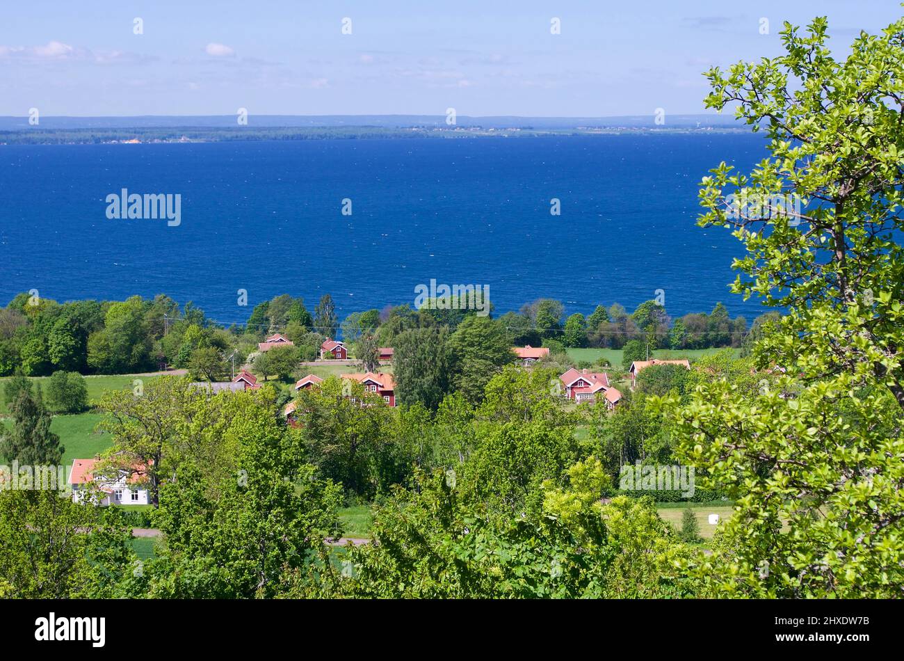 View of a lush landscape with buildings in front of the lake Vättern ...