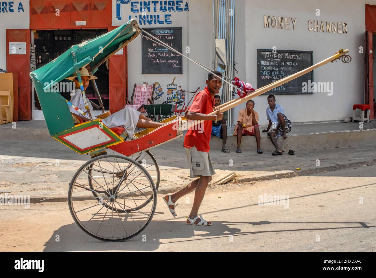Local Madagascan pulled rickshaw carrying passenger in Toliara, Madagascar, Africa Stock Photo