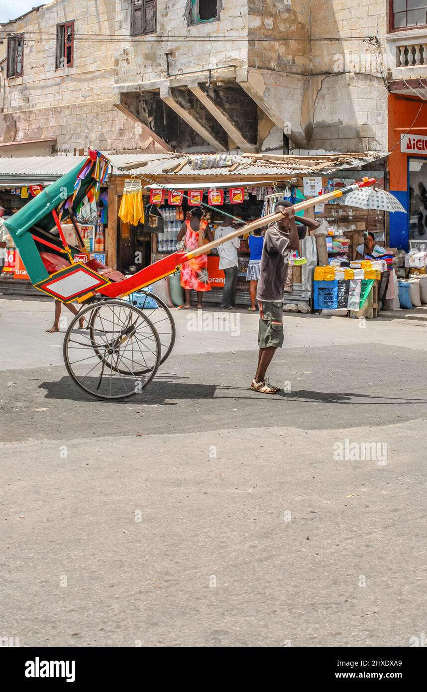 Local Madagascan pulled rickshaw carrying passenger in Toliara, Madagascar, Africa Stock Photo