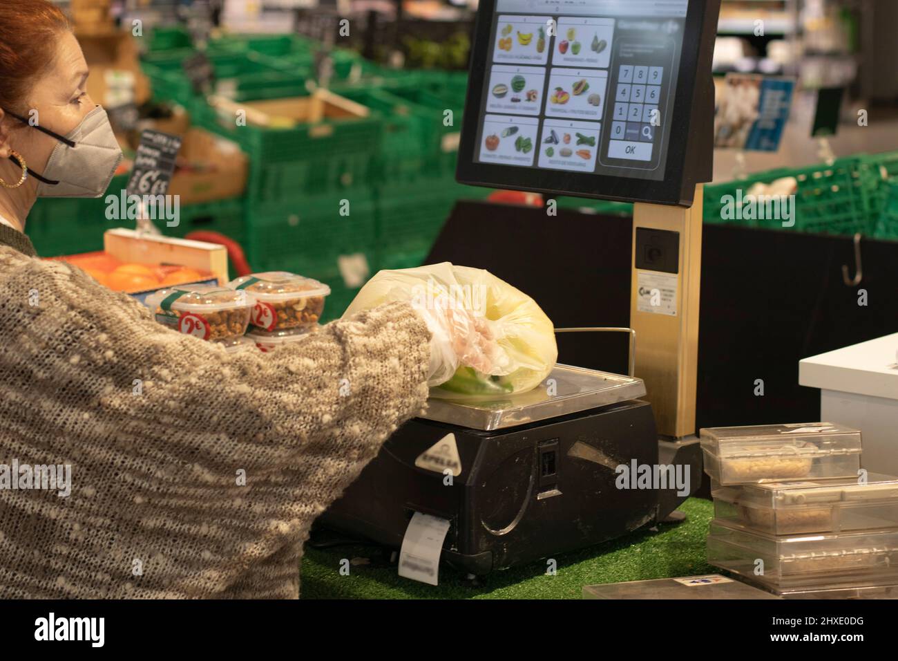 Woman weighing bananas in a plastic bag on the supermarket scale Selective focus Stock Photo