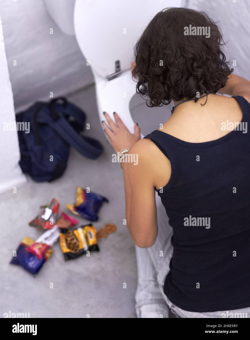 Say no to sugar. A young woman holding baked goods with her mouth covered. Stock Photo