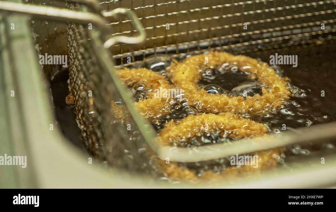 Deep fried onion ring. Oniony Rings cooking in hot bubbly oil in a