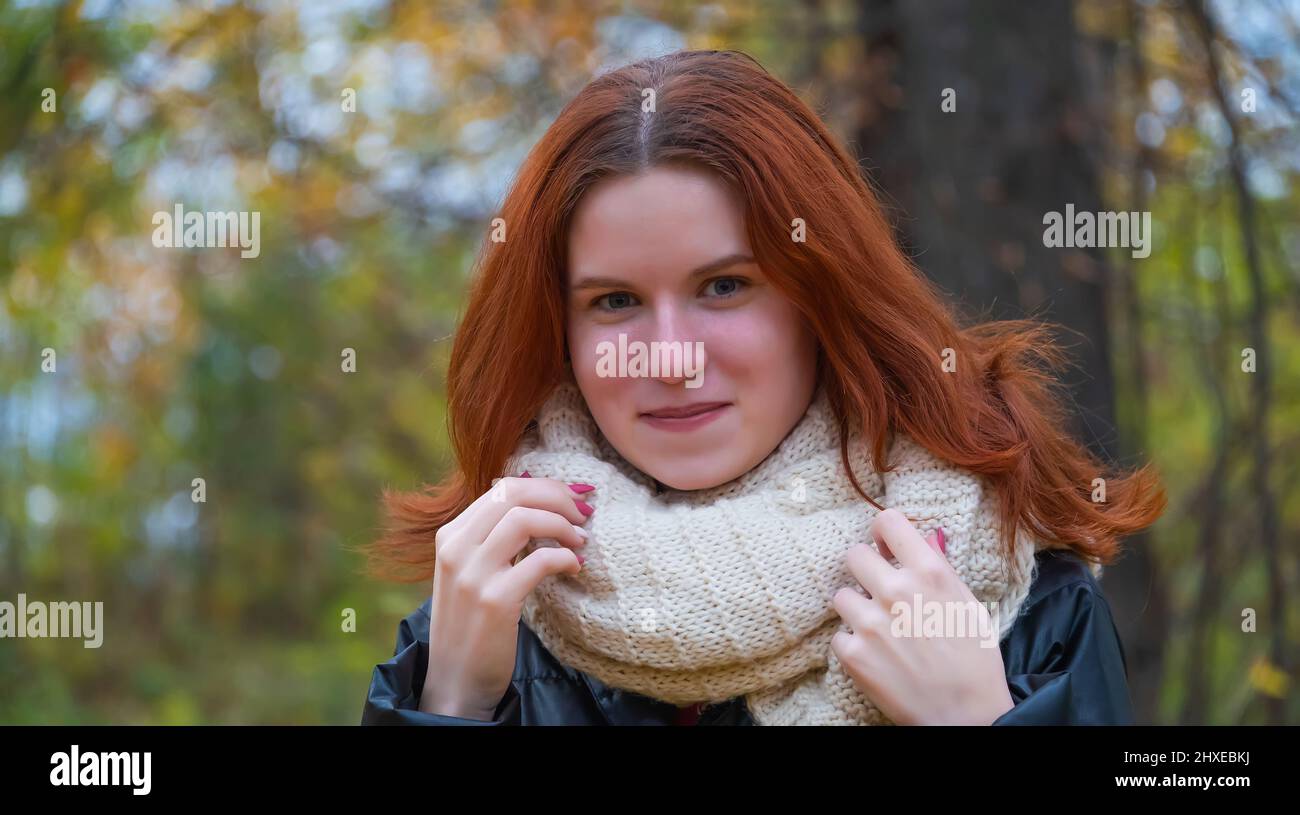 portrait of a red - haired smiling girl in a jacket smiling . against ...