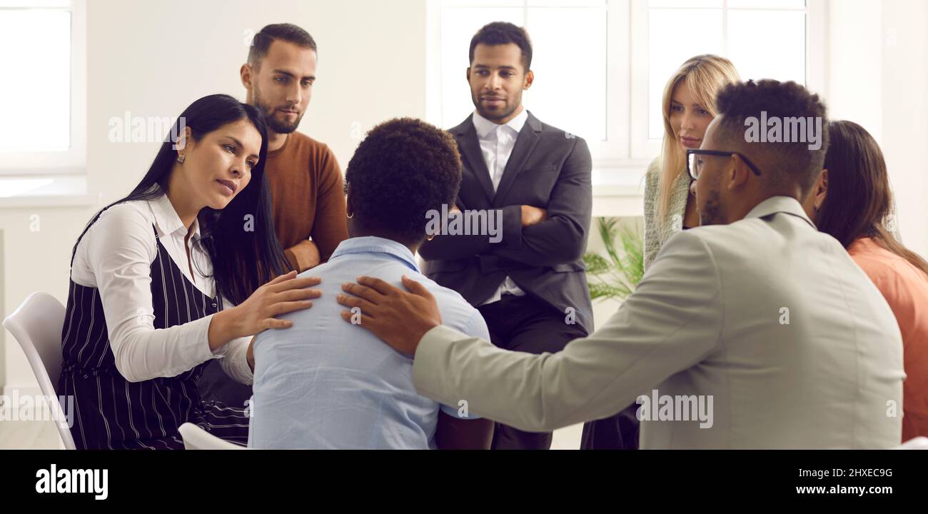 Caring people support stressed group member at counseling Stock Photo