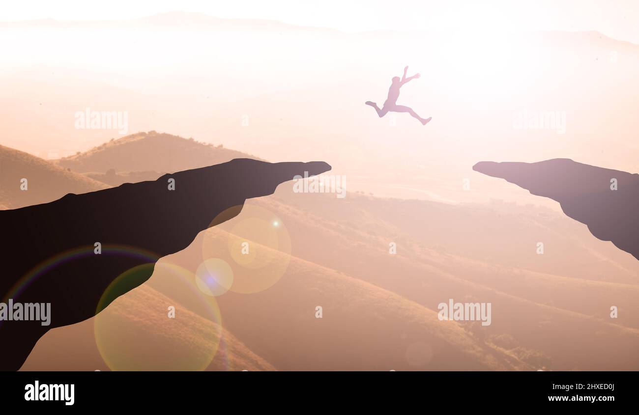 Young man Jumping off In Mountain Sunset between two cliffs. Business Gola and Ambition Concept Stock Photo