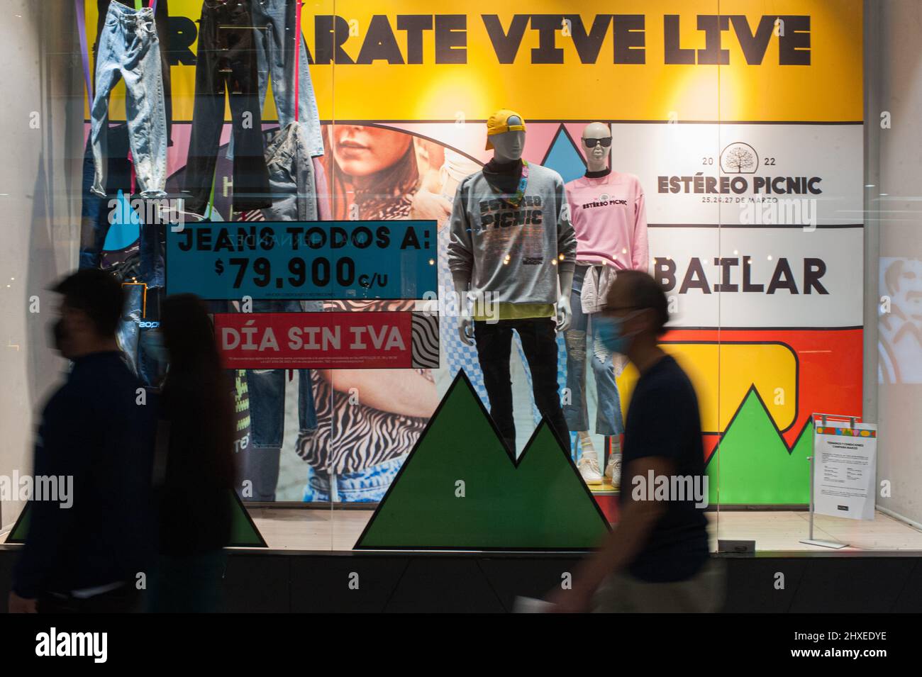 People pass by a clothing display that reads 'VAT-Free day' (Dia Sin IVA) during the first VAT-Free day of 2022 to buy clothes and electronics without a charge of 19% taxation over selected products, in Bogota, Colombia on March 11, 2022. Stock Photo