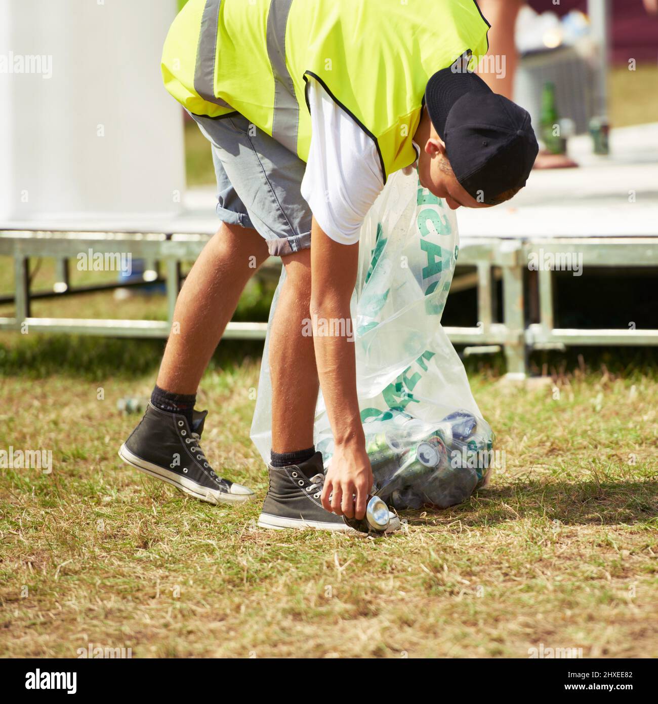 Keep it clean. Shot of a young man picking up garbage at an outdoor festival. Stock Photo