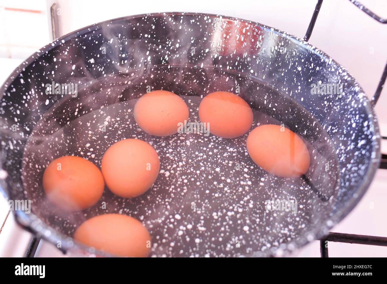 Eggs in shell in boiling water in black pot on the stove . High quality ...