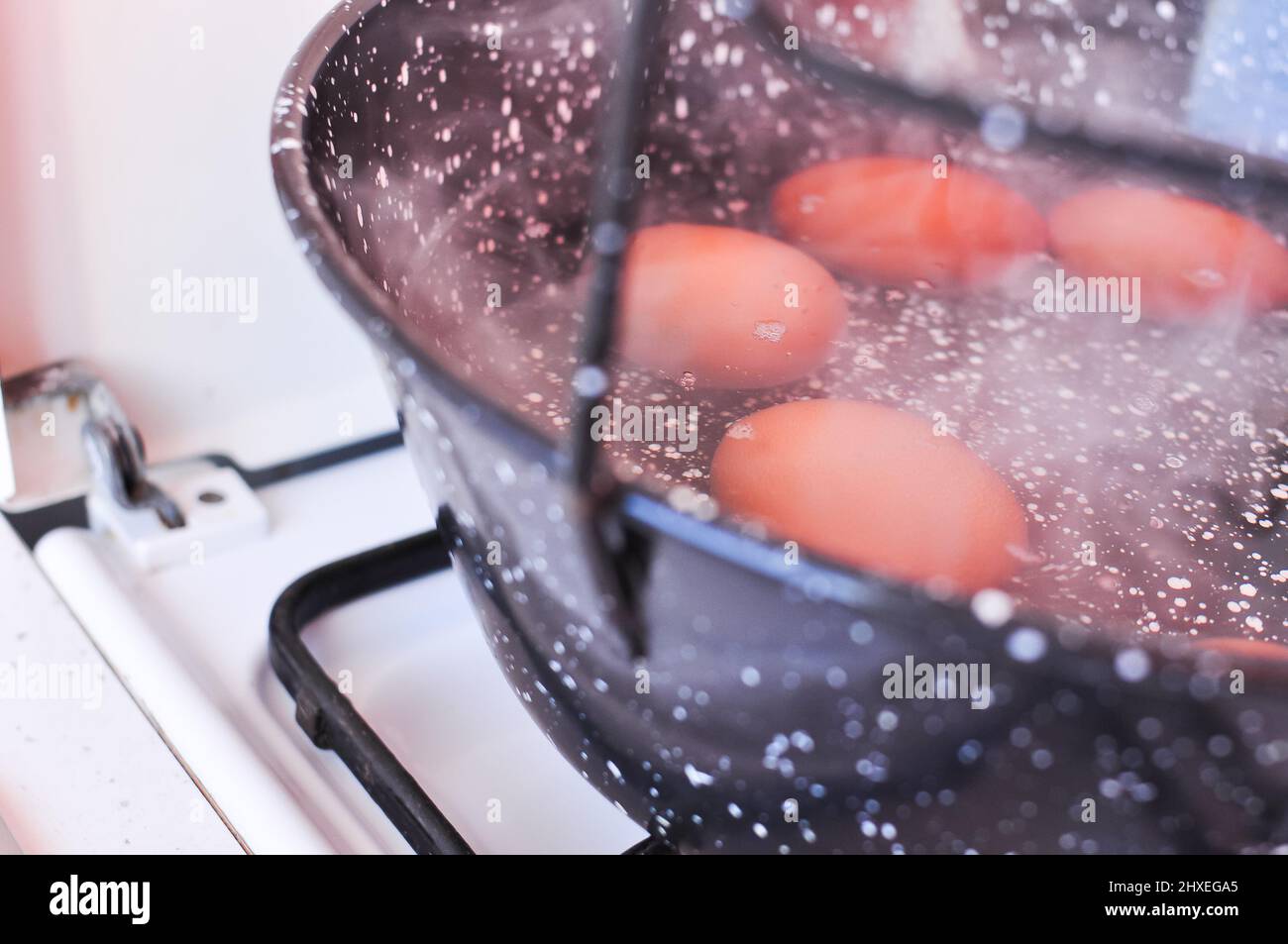 Eggs in shell in boiling water in black pot on the stove . High quality ...
