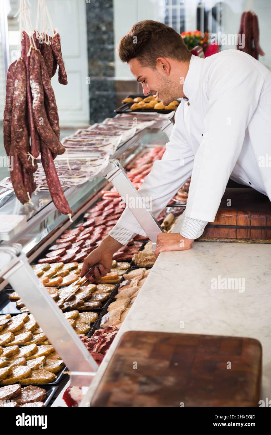 Adult happy professional cook in special clothing and cap laying out ...