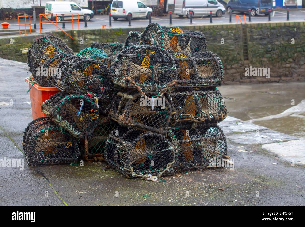 10 March 2022 Lobster Pots stacked on the quayside in the popular fishing village of Ardglass in County Down, Northern Ireland on a cold wet spring da Stock Photo