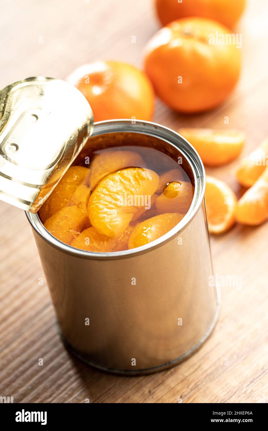 Canned tangerine. Pickled mandarin fruit in the can on wooden table. Stock Photo