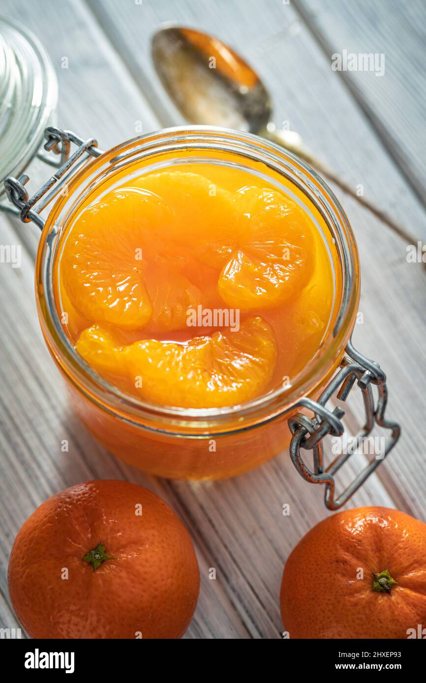 Canned tangerine. Pickled mandarin fruit in the jar on white table
