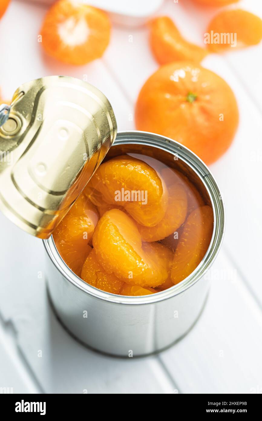 Canned tangerine. Pickled mandarin fruit in the can on white table. Stock Photo