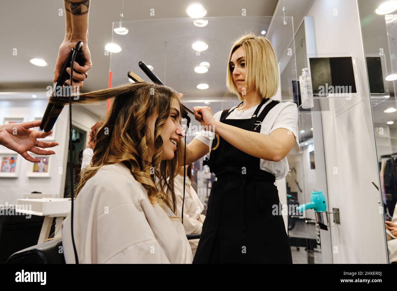 Two hairdressers doing a hairstyle to a client in a beauty salon Stock Photo Alamy