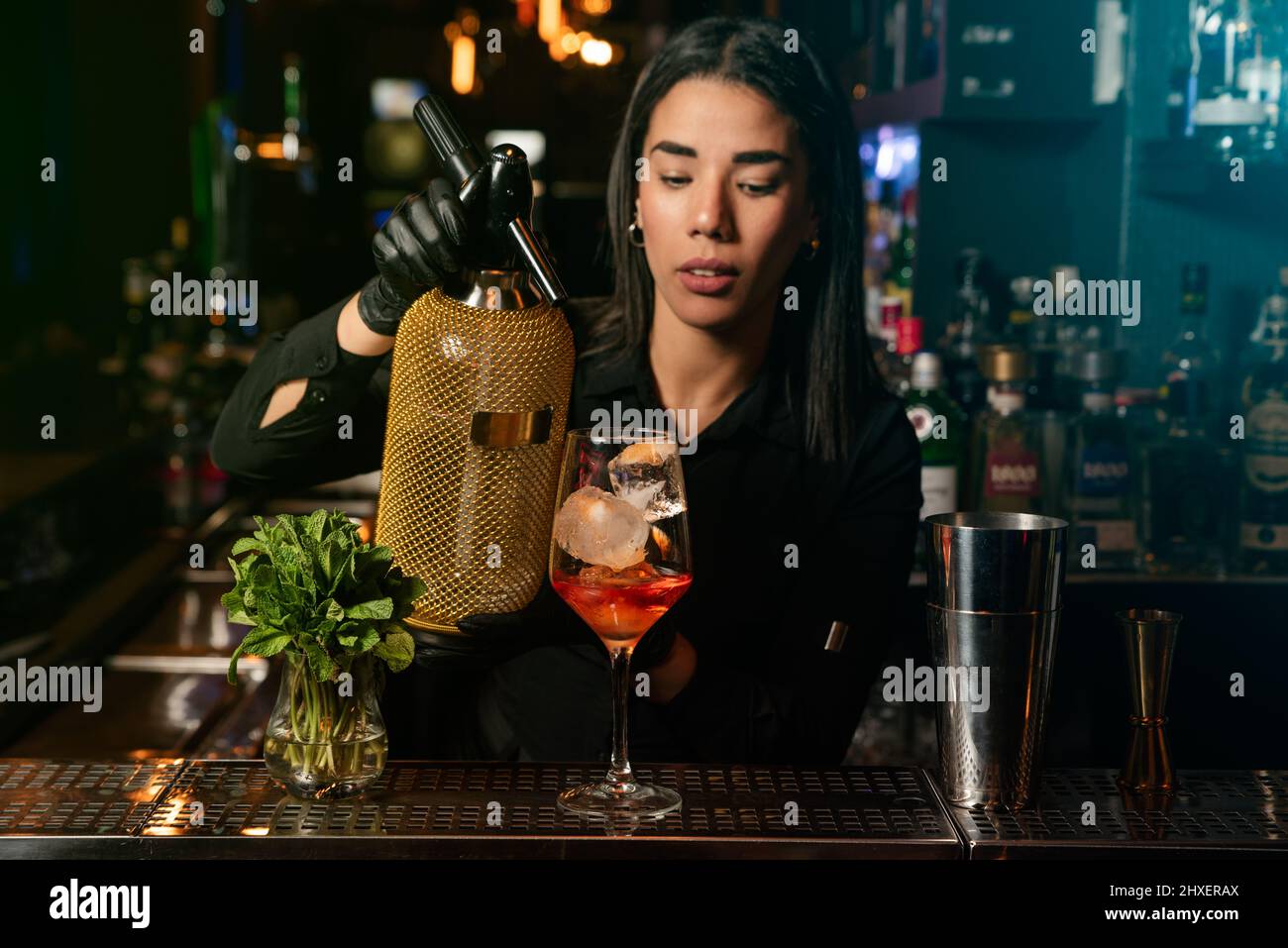 The young Latin prepares a cocktail at the bar counter. job
