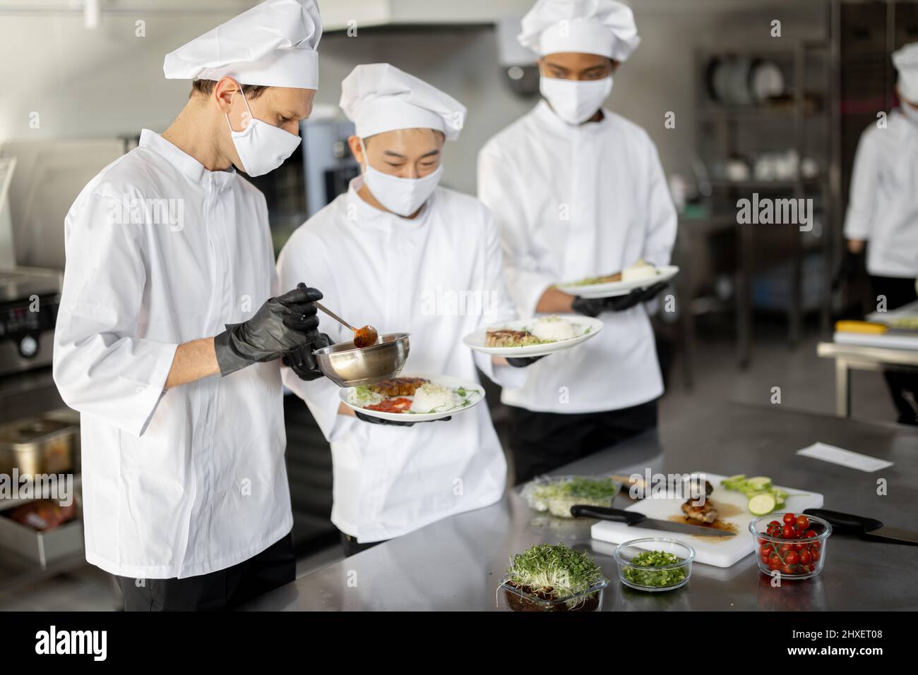 Multiracial team of cooks standing with ready meals for a restaurant in ...