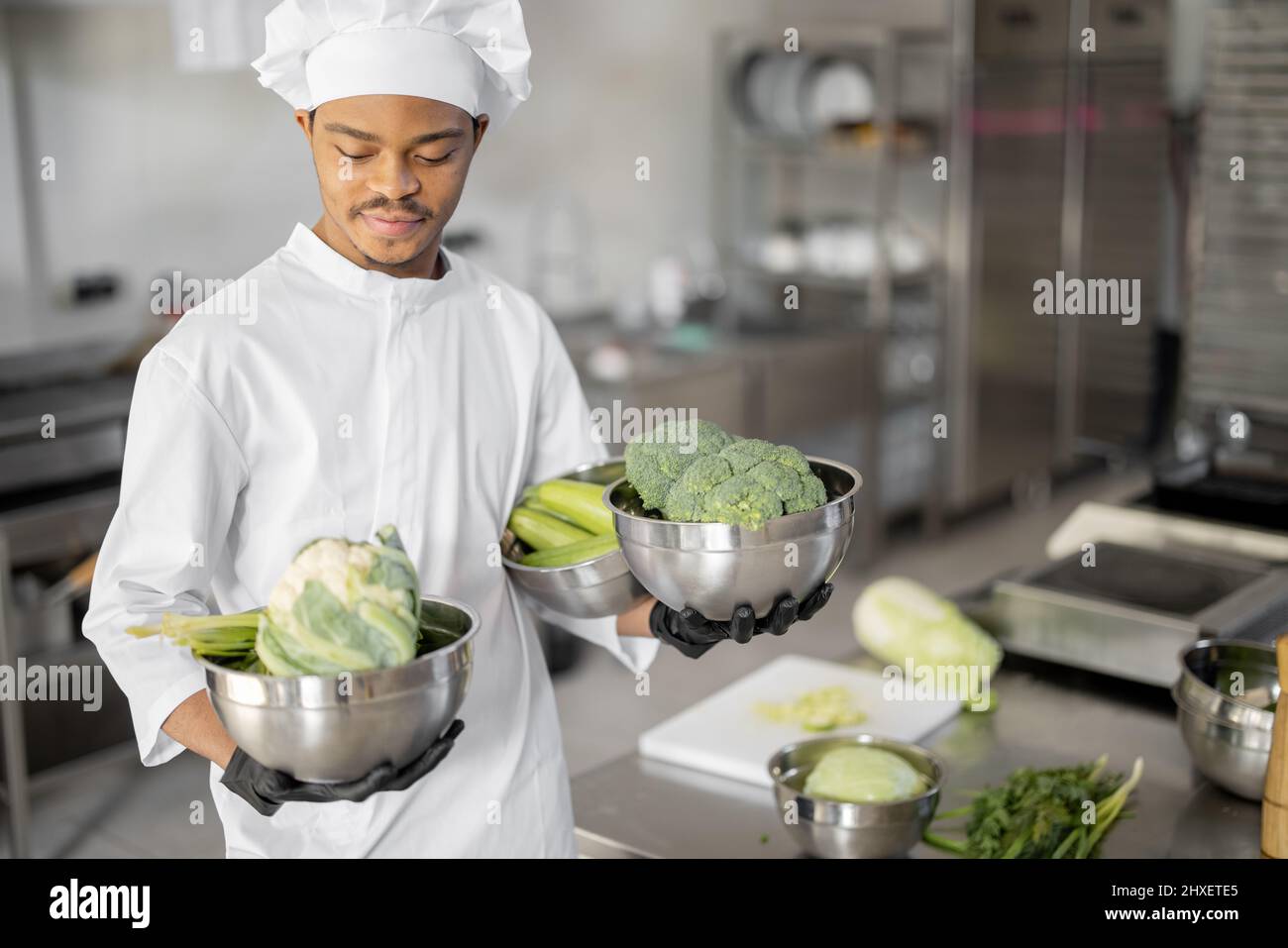 Portrait of young chef standing with healthy food ingredients, ready for cook in the restaurant
