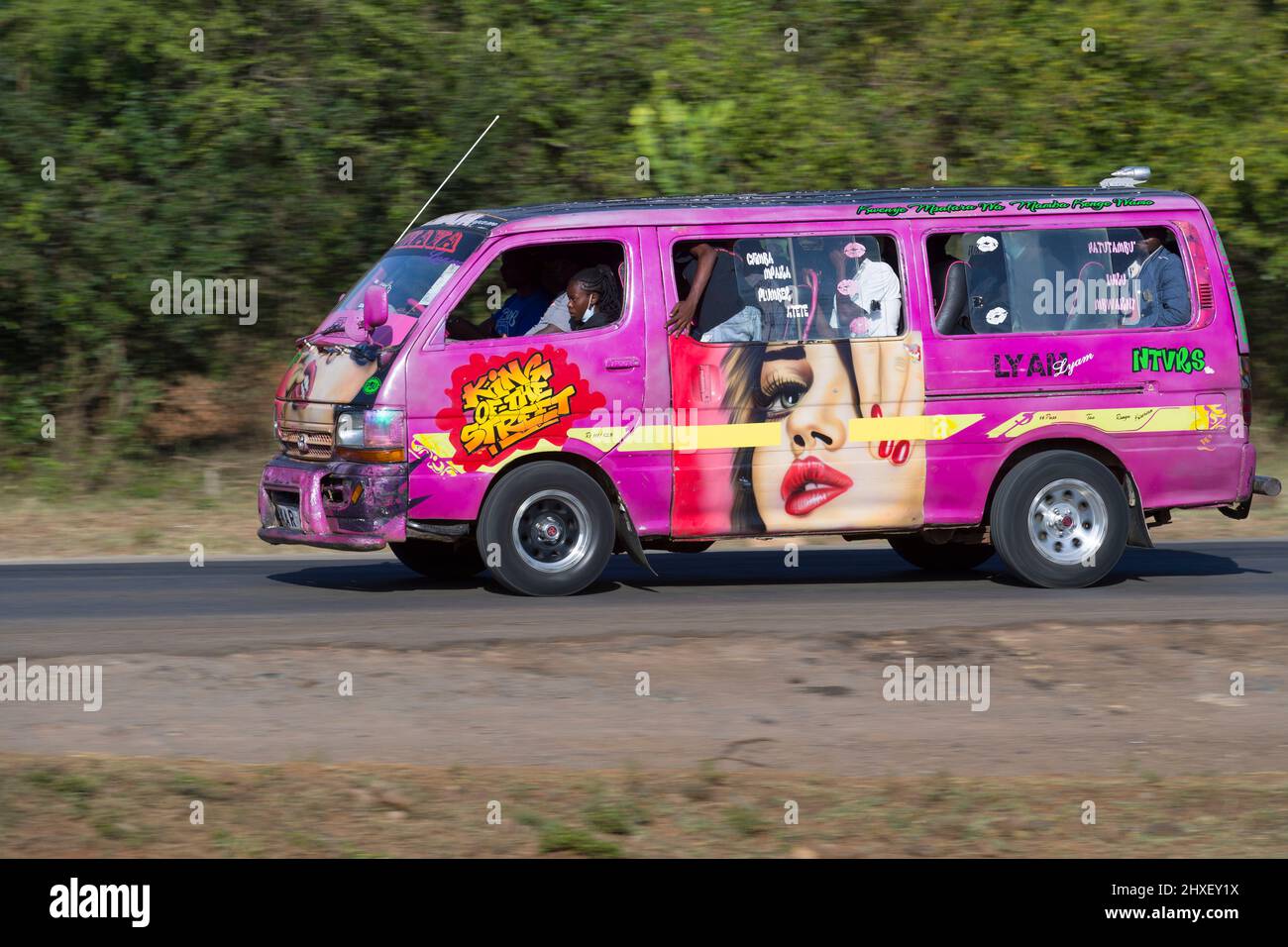 Bus with customised paintwork driving along Magadi Road, Langata. Many buses in Nairobi have custom paintwork, a wide range of subjects are painted, i Stock Photo