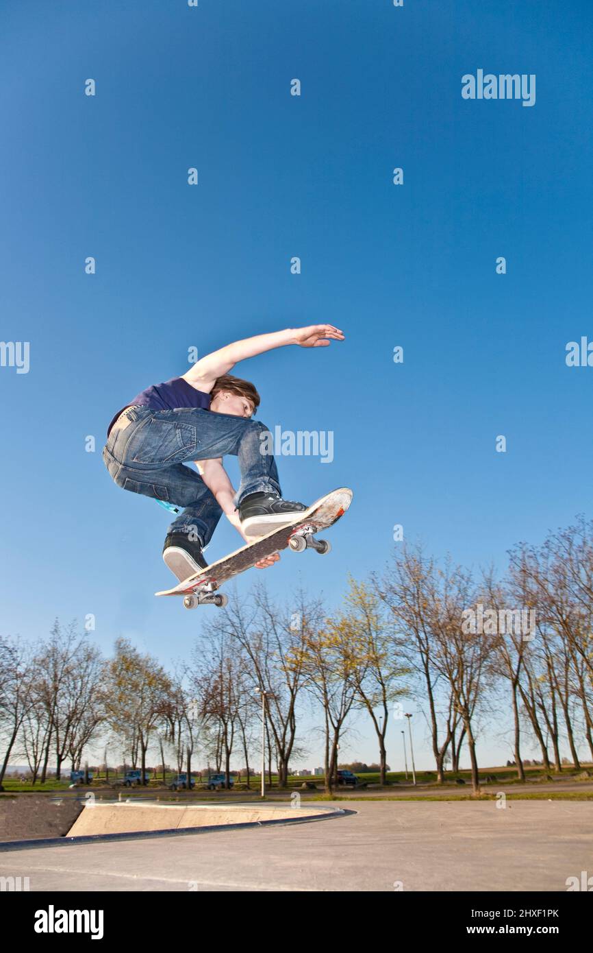 boy with skate bard is going airborne at a skate park Stock Photo
