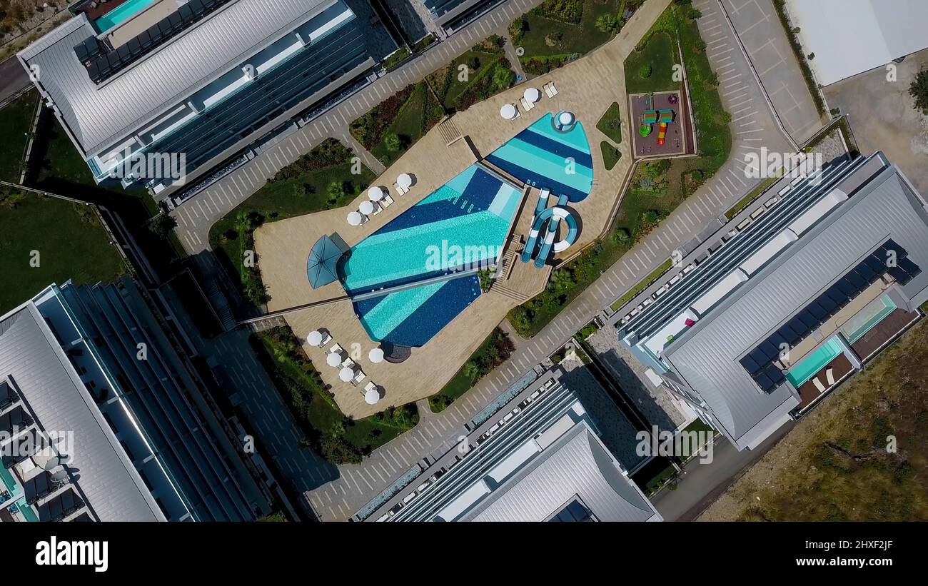 A sunny bird's-eye view. Clip. View of the resort area with a swimming pool, slides, sun umbrellas, hotels and a road for tourists Stock Photo