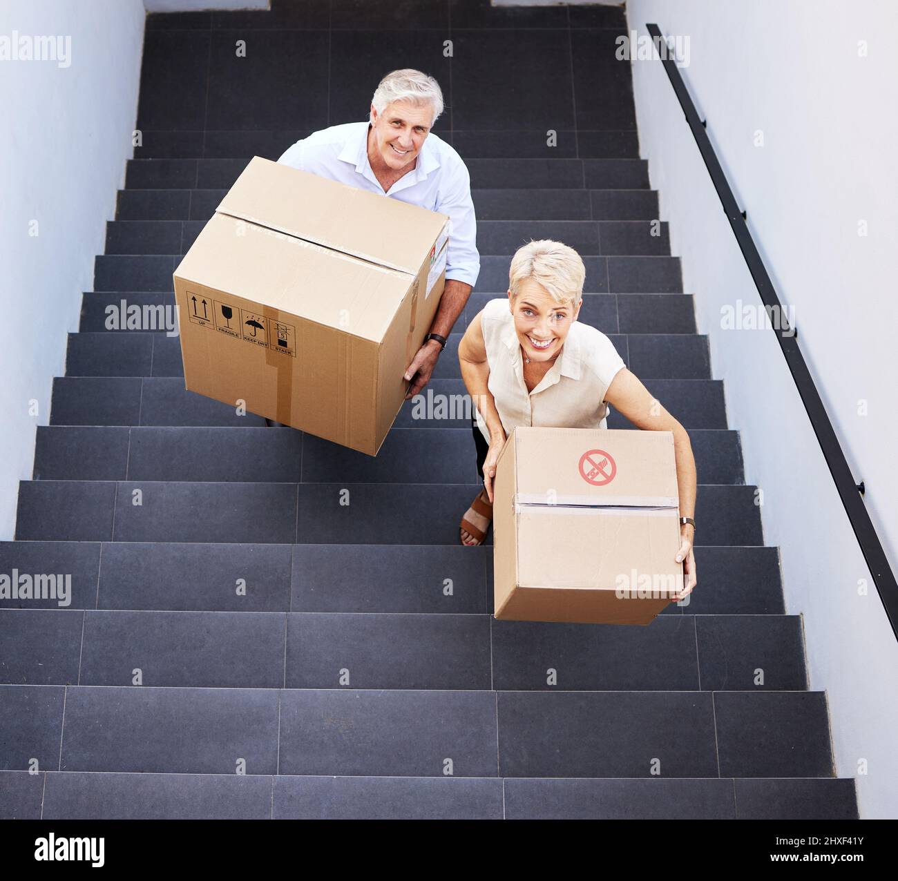 Make way for brand new memories. Shot of a mature couple carrying boxes up the stairs on moving day. Stock Photo
