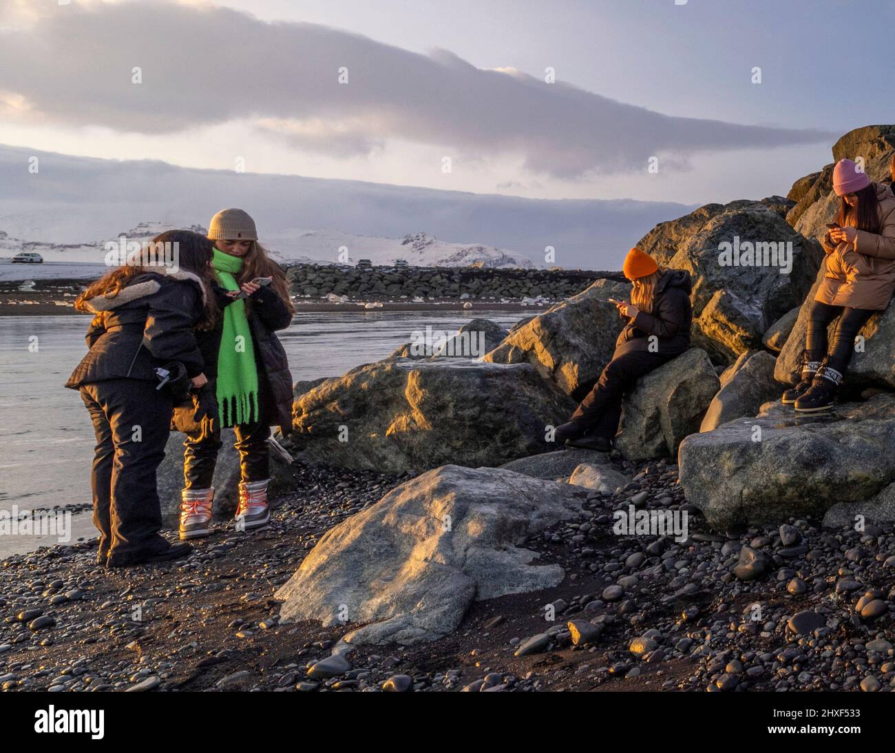 tourists outdoors ignoring nature and looking at mobile phones, Diamond Beach, Breidamerkursandur, southeast Iceland Stock Photo